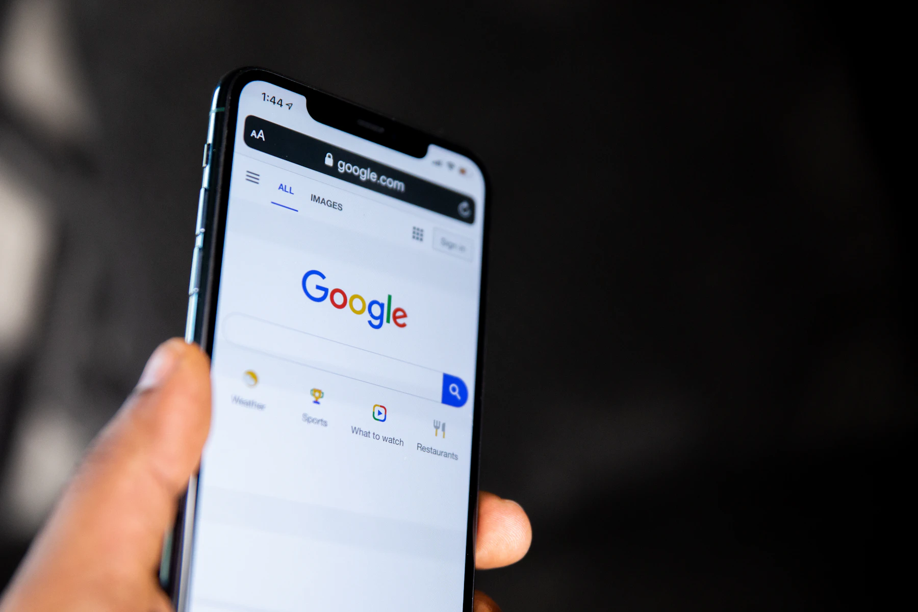 Home 2 Hand holding a phone open to Google search