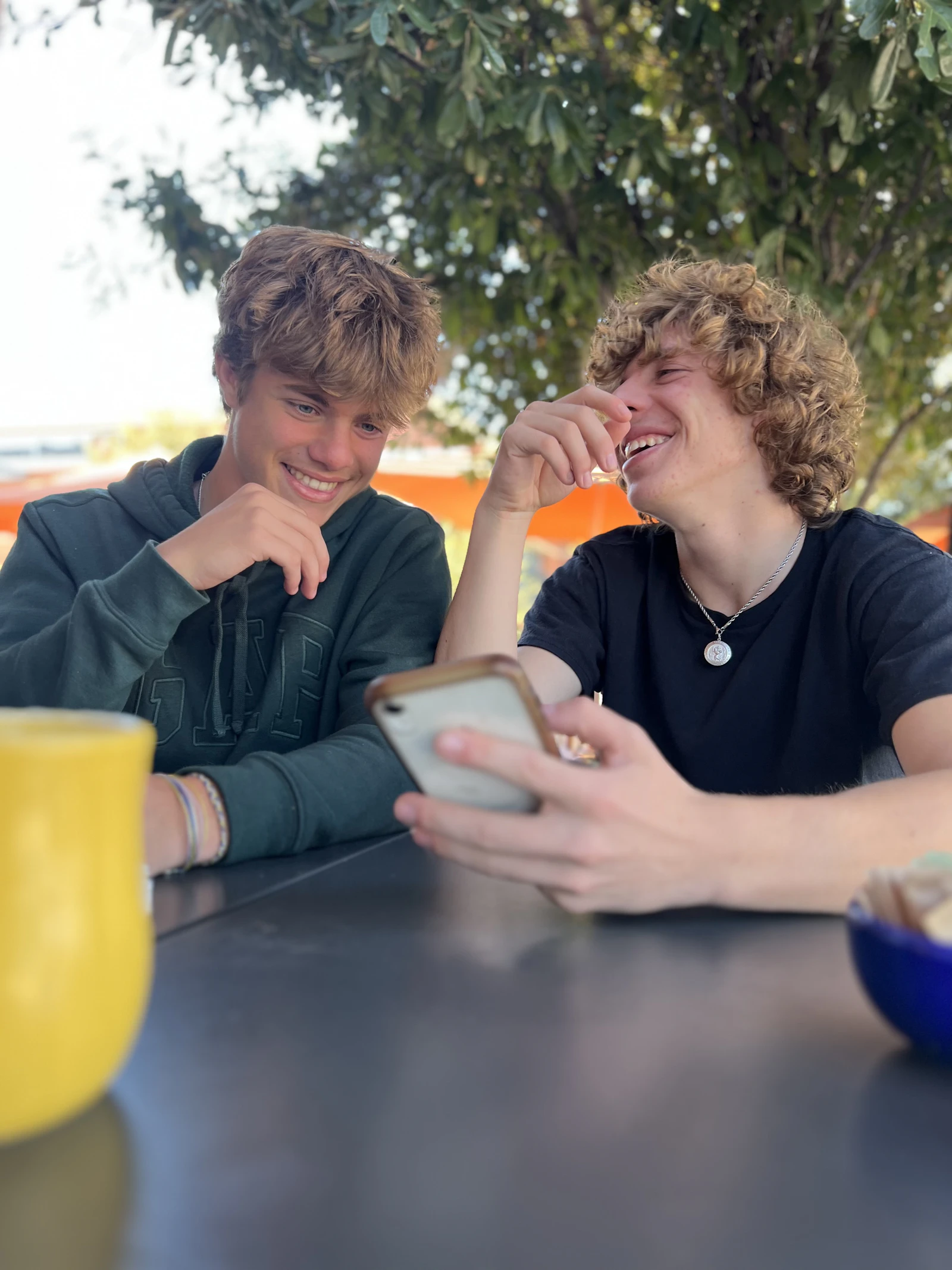 Home 1 Two teenagers laughing while looking at a phone